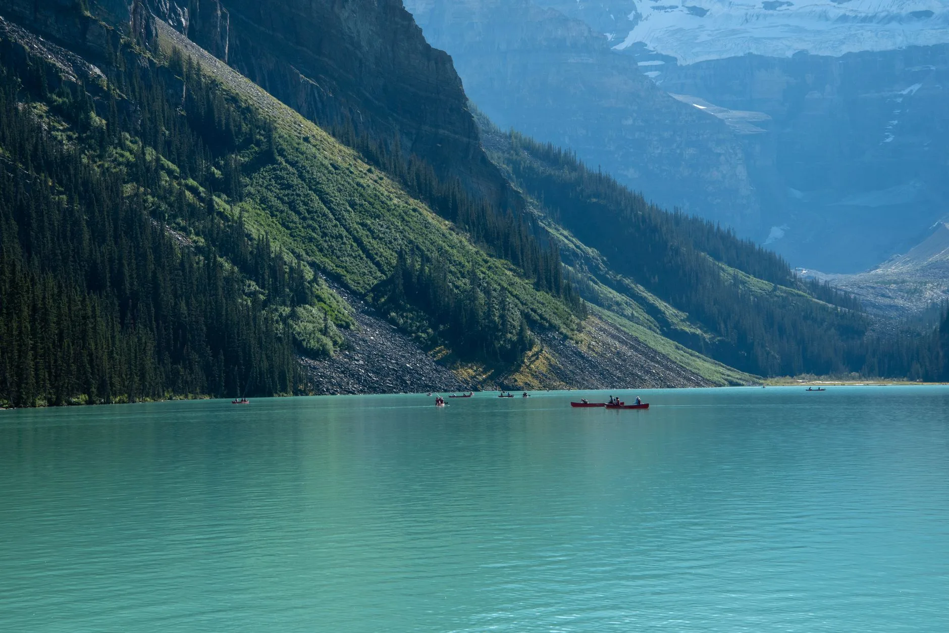 Canoës rouges sur le lac Louise turquoise entouré de montagnes des Rocheuses